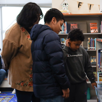 Students select a book from the library shelf to read together